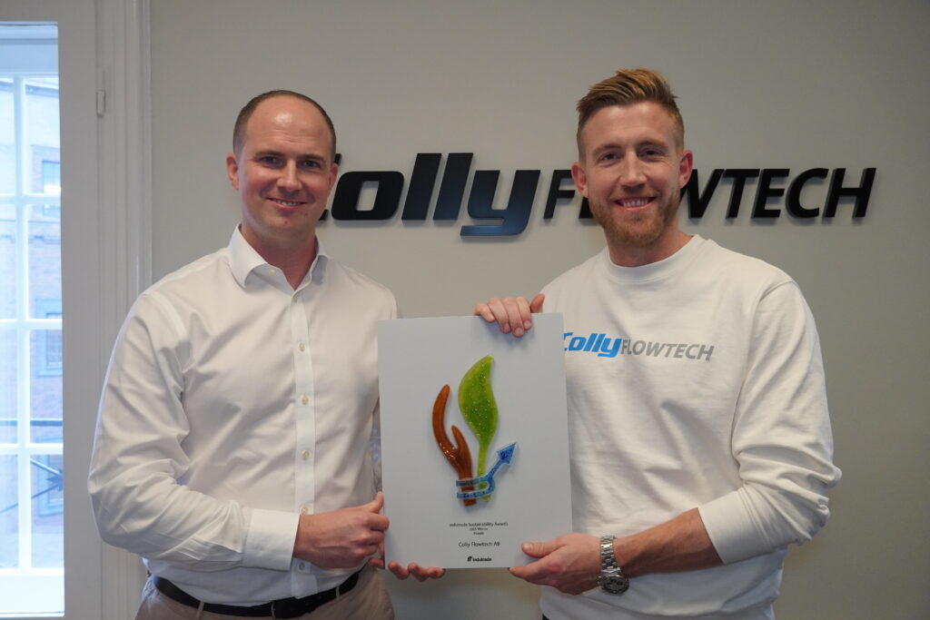 To personer står foran en væg med Colly Flowtech-logoet og holder sammen prisen fra Indutrade Sustainability Awards op.